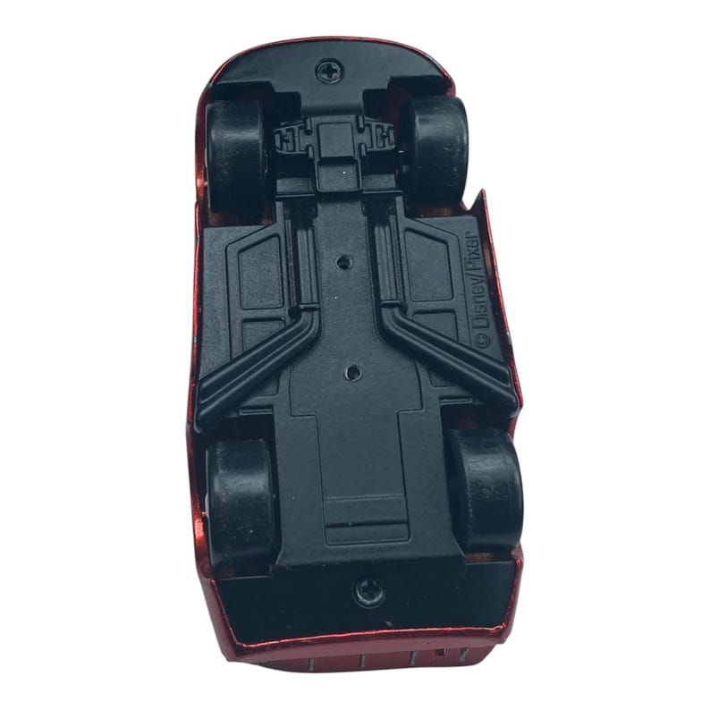 Peut inclure: Vue du dessous d'une voiture jouet rouge avec des roues noires et un ch&acirc;ssis noir. La voiture a un design a&eacute;rodynamique et est en plastique. Le logo Disney/Pixar est visible sur le c&ocirc;t&eacute;.