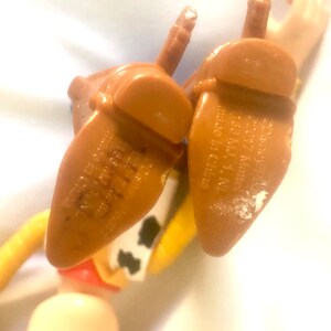 May include: Close-up of the bottom of a brown plastic toy cowboy boot with the text "Disney 22017 Mate 1158 MJ, 1, NI made in China" printed on the bottom.