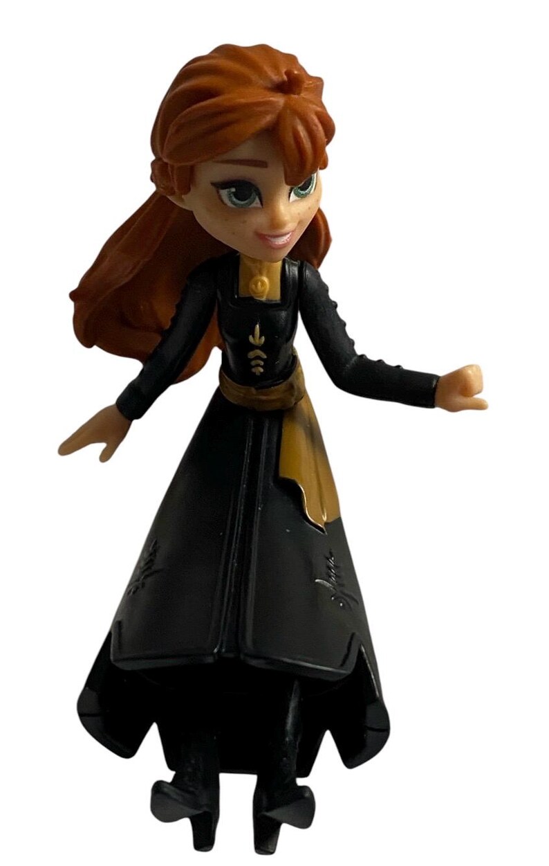 May include: A small plastic figurine of Anna from the movie Frozen wearing a black dress with gold accents and a gold belt. Her hair is long and red.