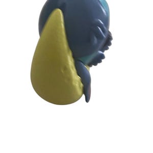 K&ouml;nnte beinhalten: Nahaufnahme einer blau-gelben Figur einer Zeichentrickfigur. Die Figur hat ein gro&szlig;es gelbes Ohr und einen blauen K&ouml;rper. Das Gesicht der Figur ist sichtbar, mit kleinen Details.
