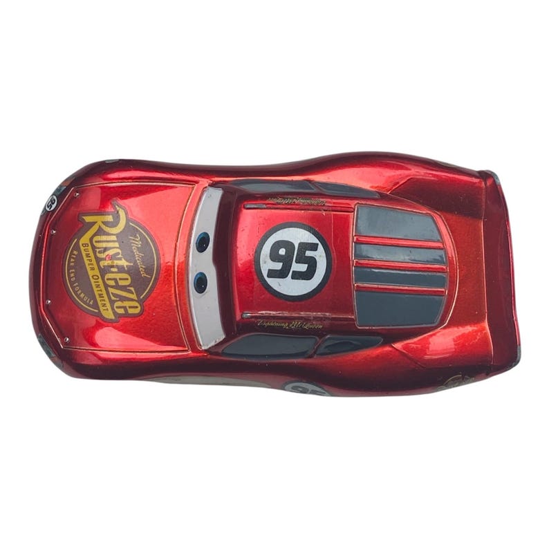 Peut inclure: Jouet de voiture Lightning McQueen rouge en m&eacute;tal moul&eacute;. La voiture porte le num&eacute;ro 95 dans un cercle blanc et le logo Rust-eze. La voiture a une finition brillante et est un personnage populaire du film Cars.