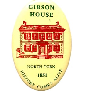 Peut inclure: Un bouton ovale jaune avec du texte vert et rouge. Le bouton présente une illustration rouge d'une maison avec le texte "Gibson House, North York 1851, History Comes Alive".