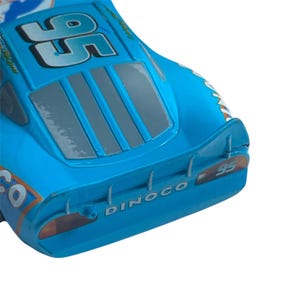 May include: Close-up of a blue toy race car with the number "95" in white and light blue on the top. The car has a "DINCO" logo and a spoiler. The car is a toy from the movie "Cars".