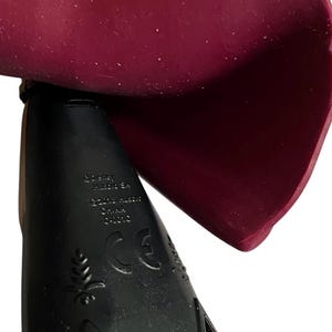 May include: Black plastic base with a burgundy cape. The base has the text "Disney", "Made in China", "CE" and a leaf design.