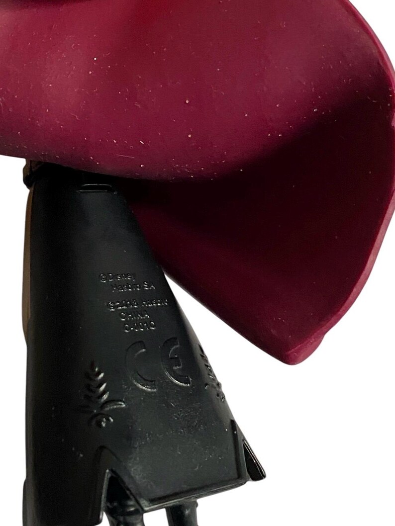 May include: Black plastic base with a burgundy cape. The base has the text "Disney", "Made in China", "CE" and a leaf design.