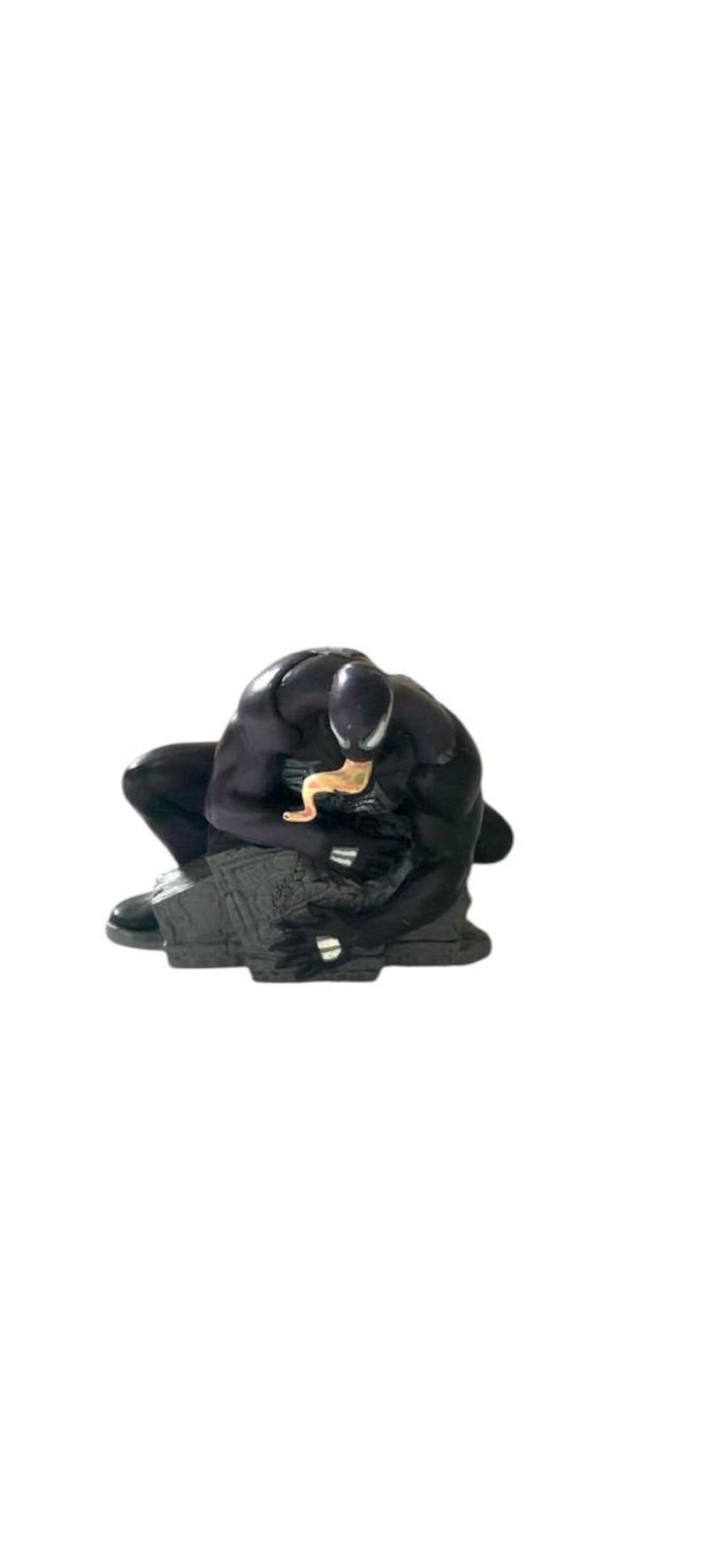 May include: Black and gray figurine of Venom, a Marvel Comics superhero, crouching on a gray base. The figurine is detailed with a black suit and a white spider symbol on the chest.