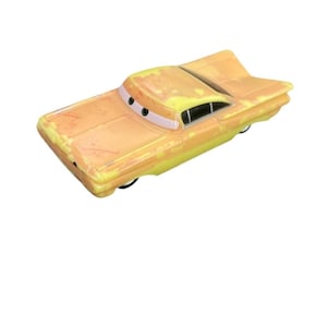 Può includere: Un'auto giocattolo pressofusa gialla e arancione, dall'aspetto usurato. L'auto presenta un design classico con una pinna e occhi da cartone animato. L'auto giocattolo è un oggetto da collezione. L'auto misura circa 15 cm di lunghezza.