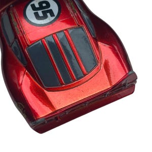 Peut inclure: Une voiture de course jouet rouge avec le num&eacute;ro 95 dans un cercle blanc. La voiture a une finition brillante et pr&eacute;sente des accents noirs et gris. C'est un mod&egrave;le moul&eacute; sous pression.