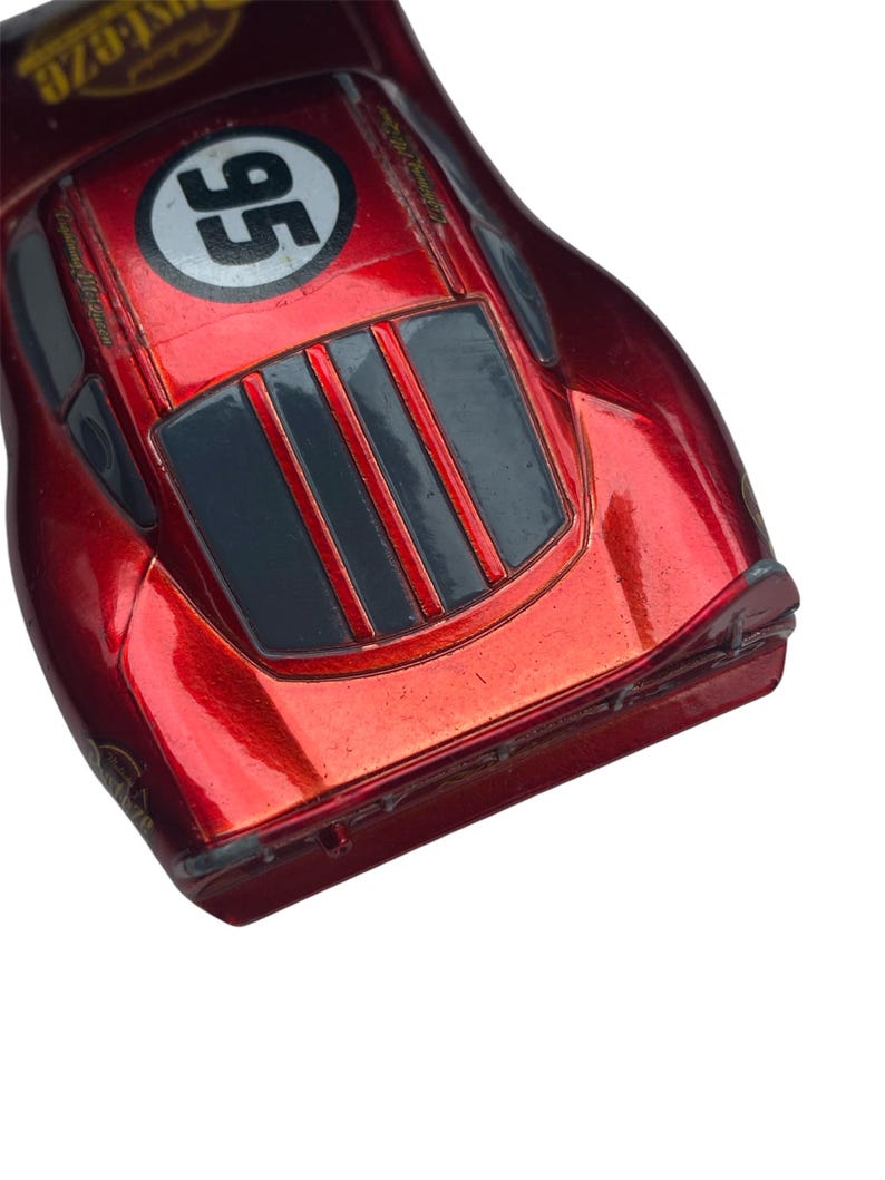 Peut inclure: Une voiture de course jouet rouge avec le num&eacute;ro 95 dans un cercle blanc. La voiture a une finition brillante et pr&eacute;sente des accents noirs et gris. C'est un mod&egrave;le moul&eacute; sous pression.