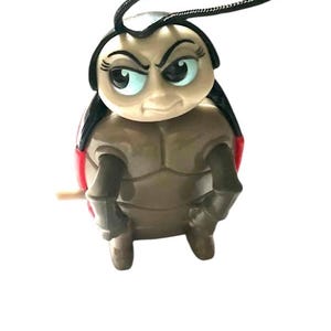 May include: A brown and red ladybug toy with black eyes and a black antenna. The ladybug has a grumpy expression on its face.