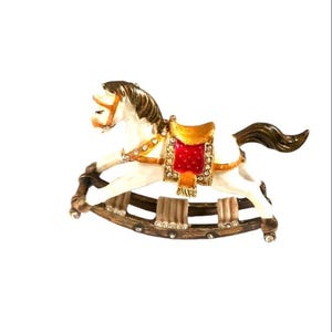 May include: A white rocking horse with a red and gold saddle, decorated with rhinestones. The horse is on a wooden base with a brown finish.