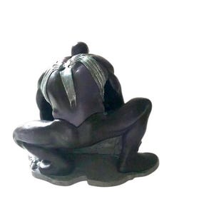 May include: A black and silver action figure of a superhero in a crouching pose. The figure has a webbed design on its back and is posed as if it is about to attack.