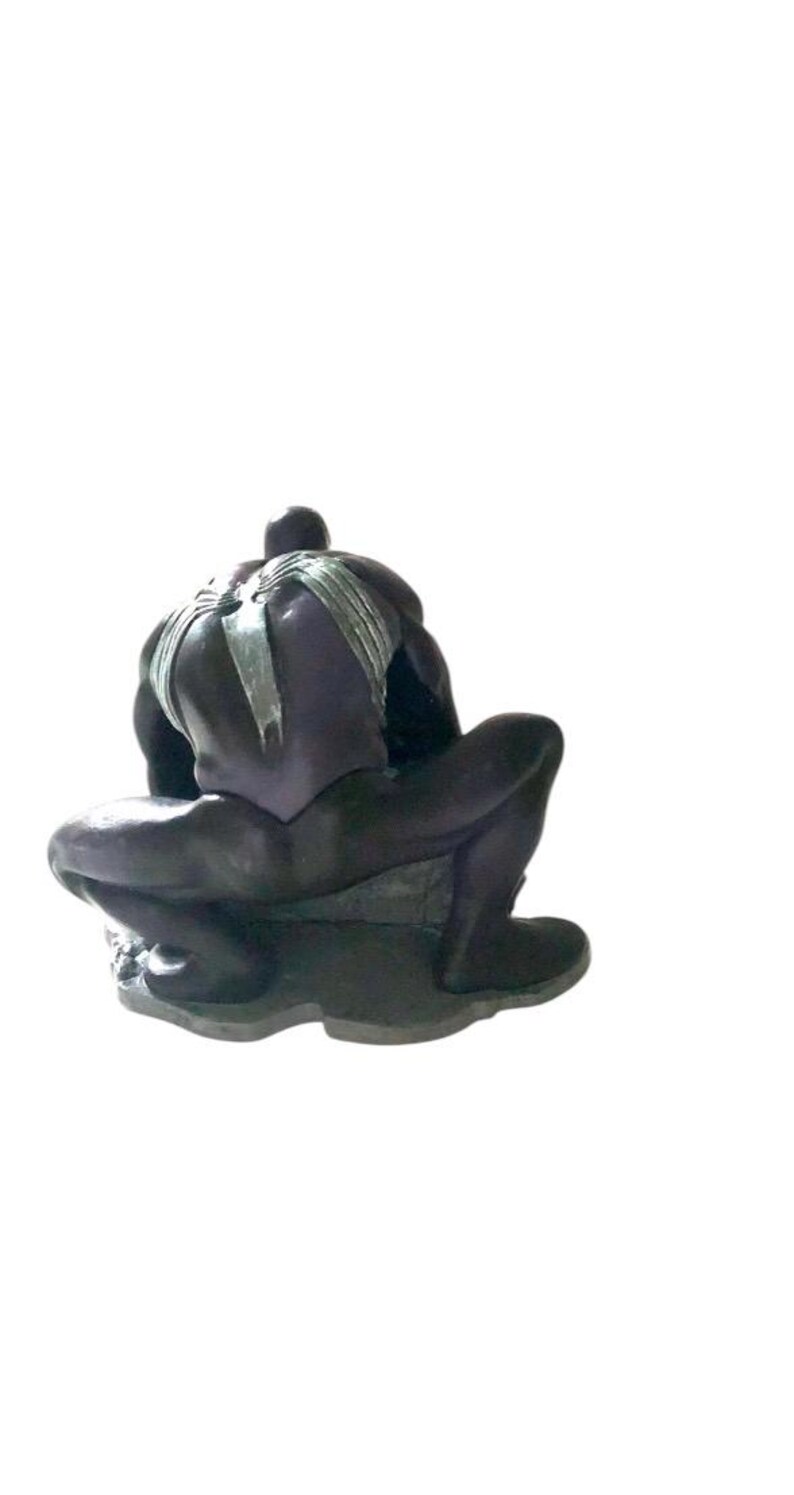 May include: A black and silver action figure of a superhero in a crouching pose. The figure has a webbed design on its back and is posed as if it is about to attack.