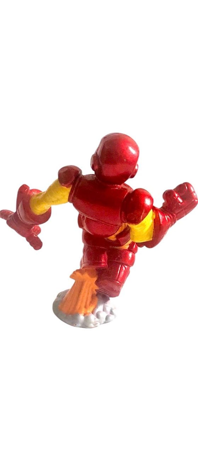 以下が含まれることがあります： 赤いと黄色のアイアンマンのアクションフィギュアがジェットパックで飛んでいます。フィギュアは、片腕を伸ばし、もう片方の手でリパルサービームを持っている、ダイナミックなポーズをとっています。