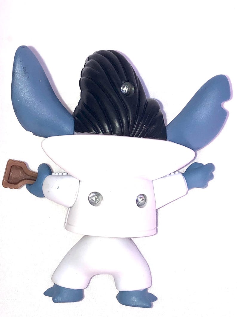 May include: Blue and white plastic figurine of a character wearing a white suit and a black hairpiece. The character is holding a brown guitar in its right hand.