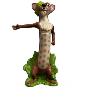 May include: A figurine of the character Buck from the animated film Ice Age. The figure has a brown body with tan spots, a cream-colored chest, and a green eye patch. It is standing on a green leaf base.
