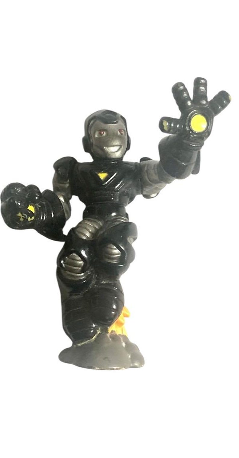 K&ouml;nnte beinhalten: Eine schwarze und silberne Actionfigur eines Superhelden, der einen schwarzen Anzug mit einem gelben Dreieck auf der Brust tr&auml;gt. Die Figur steht auf einem grauen Sockel mit einem gelben Flammenmuster. Die Figur hat ein gelbes Licht in der Hand.