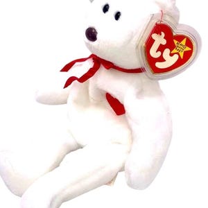 May include: White plush beanie baby bear with a red ribbon around its neck. The bear is sitting with its legs outstretched. The bear has a Ty tag attached to its ear that says "Beanie Babies".