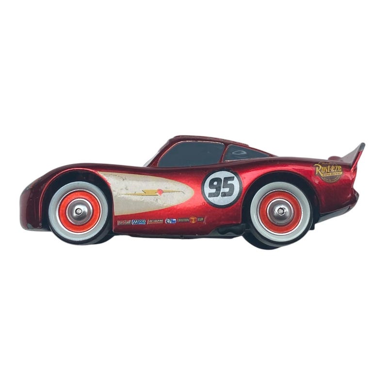 Peut inclure: Une voiture de course jouet rouge avec le num&eacute;ro 95 sur le c&ocirc;t&eacute;. La voiture a des roues &agrave; jantes blanches et un aileron. La voiture a une finition m&eacute;tallique et est un personnage de Flash McQueen du film Cars.