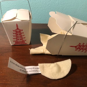 May include: Two white takeout containers with red pagoda designs and a white fortune cookie with a paper slip that reads "It is our attitude at the beginning of a difficult task that will affect its successful outcome."