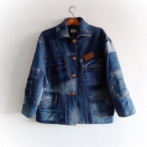 May include: A blue denim jacket with a patchwork design. The jacket has multiple pockets and a button closure.