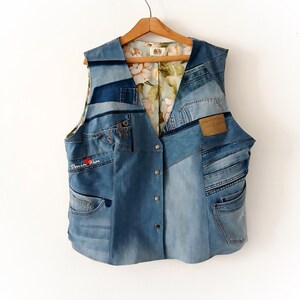 May include: A sleeveless vest constructed from various shades of blue denim fabric patches. The garment features a front button closure, multiple pockets, and a light-colored interior lining with a floral pattern. The text Denim Wear is visible.