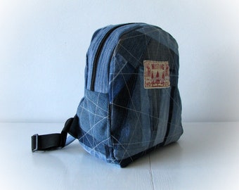 May include: A small blue denim backpack with a black strap and a rectangular patch that says "MISSING" in red letters.