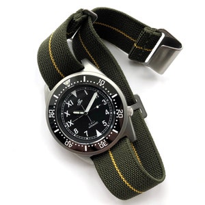 Puede incluir: Un reloj de pulsera de acero inoxidable con esfera negra y correa de nailon verde con una raya amarilla. La esfera del reloj presenta números y agujas blancos, con el texto "CALL AUTOMATIC".