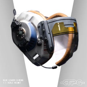 Op de afbeelding: Een gedetailleerde, gebroken witte en grijze helm met blauwe en bruine accenten, met een helder vizier met een gele tint. De helm heeft een microfoon en is voorzien van het opschrift "BLUE LEADER B-WING 1:1 SCALE HELMET".