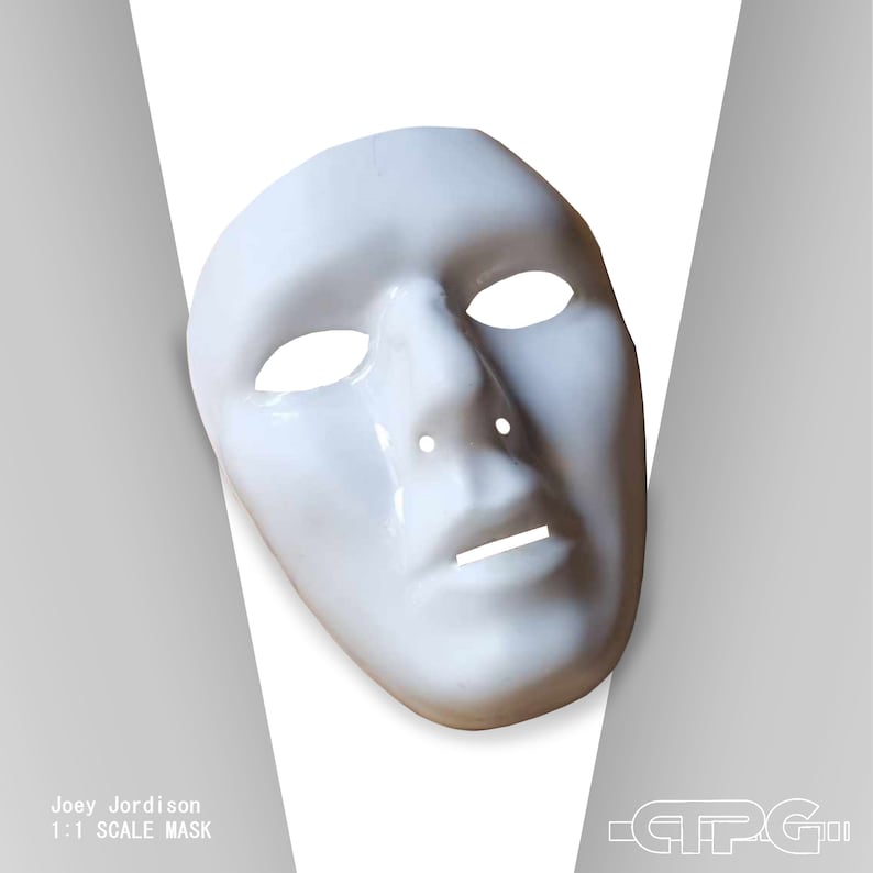 May include: A white, full-face mask with eye and mouth openings. The mask has a smooth, glossy finish and is designed to fit the contours of a human face. Text on the image reads "Joey Jordison 1:1 SCALE MASK".