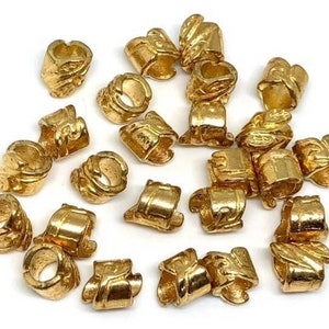 May include: A collection of 20 gold-toned metal bead caps with a decorative design. The caps are approximately 1/2 inch in diameter and have a hole in the center for threading.