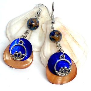 May include: A pair of dangle earrings with a blue and copper shell design. The earrings feature a silver charm with a wave design and a blue and brown bead.