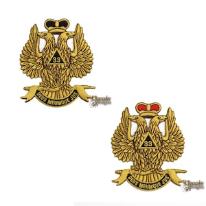 Op de afbeelding: Twee gouden geborduurde patches met een ontwerp van een dubbelkoppige adelaar. De adelaar houdt een driehoek vast met het nummer 33 erin. De tekst "DEUS MEUMQUE JUS" staat op een banner onder de adelaar.