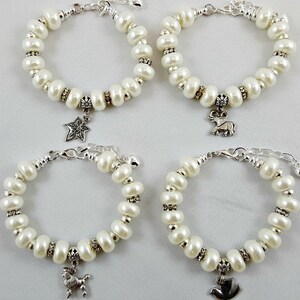 May include: Four white pearl bracelets with silver charms. The charms are a star, a deer, a bird, and a rooster.