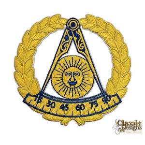 Op de afbeelding: Een gouden geborduurde patch met een vrijmetselaars symbool. Het symbool is een passer en een winkelhaak in een driehoek met een zon in het midden. Het symbool is omgeven door een krans van bladeren.