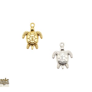 Op de afbeelding: Twee schildpadbedels, een gouden en een zilveren, met gedetailleerde schelpontwerpen. Deze bedels zijn perfect voor het maken van sieraden of om een ​​toets van whimsy toe te voegen aan ambachten.