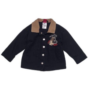 May include: A dark navy blue jacket featuring a tan corduroy collar, long sleeves, and a front button closure. The chest displays an embroidered graphic of Minnie Mouse with a leopard print bow and the script text minnie above red roses.