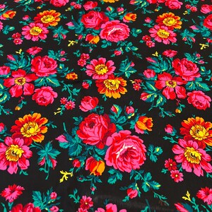 May include: Black fabric with a repeating pattern of pink, red, yellow, and green flowers. The flowers are stylized and have a vintage look.