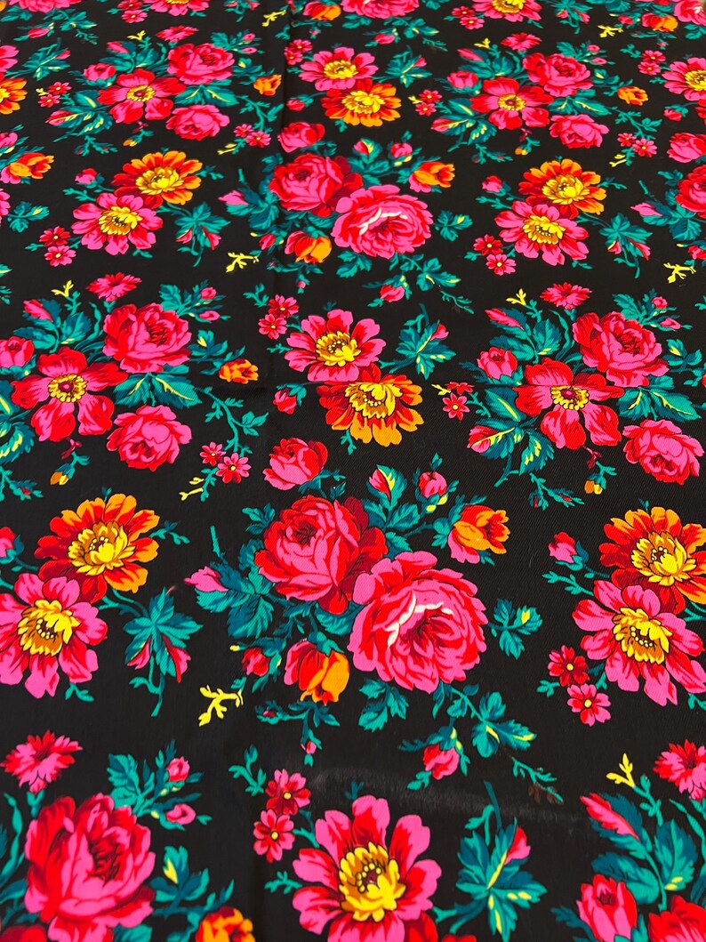 May include: Black fabric with a repeating pattern of pink, red, yellow, and green flowers. The flowers are stylized and have a vintage look.