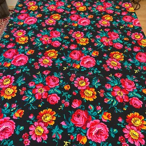 May include: Black fabric with a repeating pattern of pink, red, yellow, and green flowers. The flowers are stylized and have a vintage look.