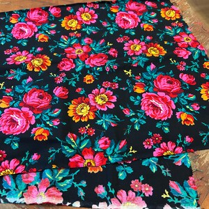 May include: Two pieces of black fabric with a floral pattern. The fabric features pink, red, yellow, and green flowers on a black background.