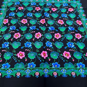 Pode incluir: Tecido preto com um padrão floral em tons de rosa, azul e verde. As flores são dispostas em um padrão repetitivo sobre um fundo preto.