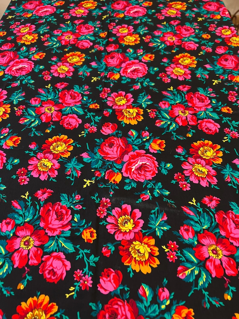 May include: Black fabric with a repeating floral pattern. The flowers are pink, red, yellow, and orange with green leaves.