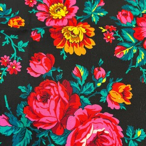 May include: Black fabric with a floral pattern featuring pink, red, yellow, and green roses. The fabric has a textured surface.