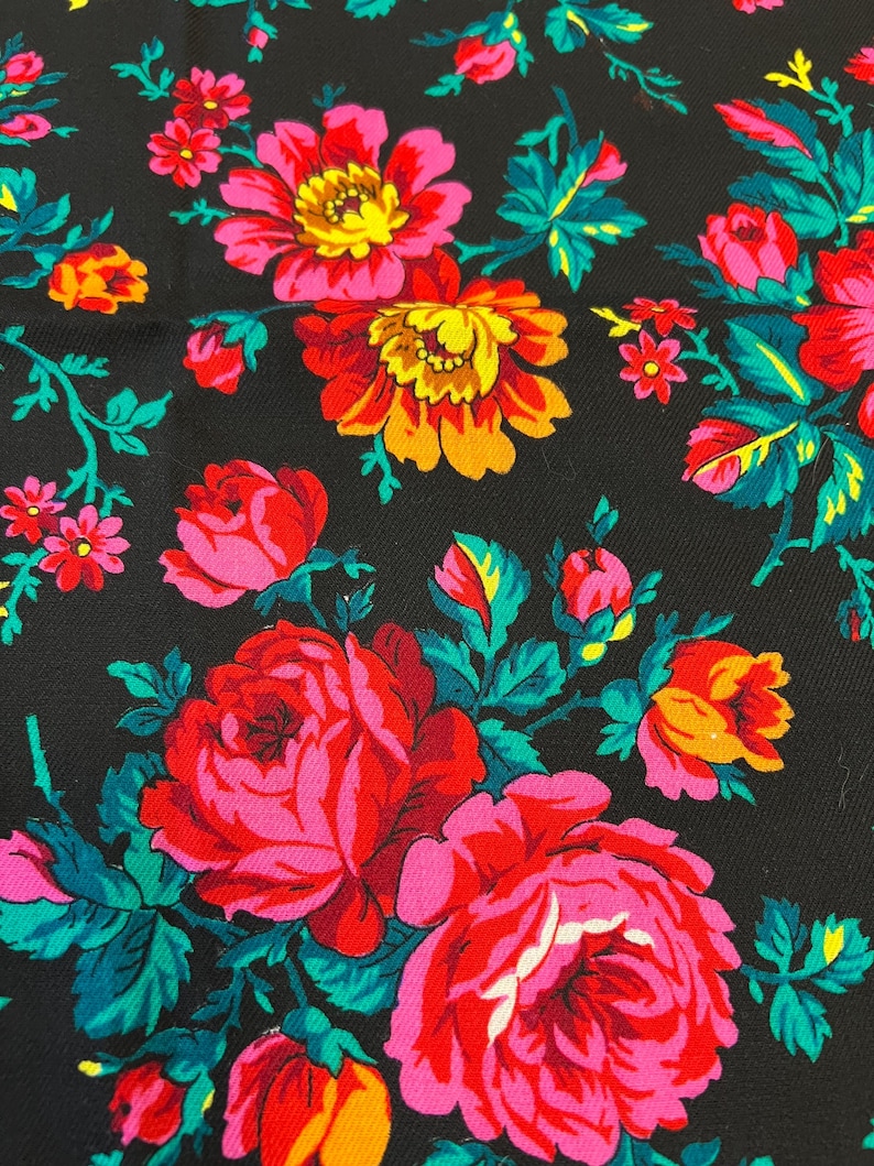 May include: Black fabric with a floral pattern featuring pink, red, yellow, and green roses. The fabric has a textured surface.