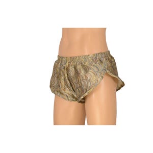 以下が含まれることがあります： ゴールドとグリーンのパターンが施されたアスレチックショーツで、フリルトリムが付いています。ショーツはドローストリングウエストバンドとサイドスリットが付いています。