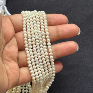 Puede incluir: Una hebra de perlas de agua dulce blancas, de aproximadamente 4-5 mm de tama&ntilde;o, enhebradas en un hilo blanco. Las perlas son redondas y tienen un acabado liso y brillante.