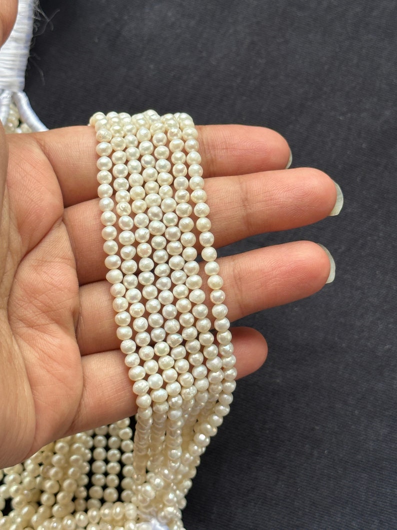 Puede incluir: Una hebra de perlas de agua dulce blancas, de aproximadamente 4-5 mm de tama&ntilde;o, enhebradas en un hilo blanco. Las perlas son redondas y tienen un acabado liso y brillante.