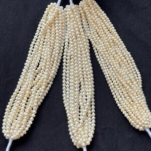 Puede incluir: Una hebra de perlas de agua dulce blancas, con m&uacute;ltiples hebras de perlas agrupadas. Las perlas son peque&ntilde;as y redondas, y la hebra es larga.