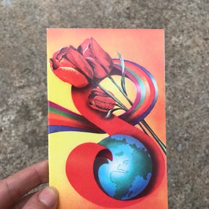 May include: A vintage postcard with a colorful design featuring a globe, tulips, and a rainbow. The globe is blue with green continents and is surrounded by a red, orange, and yellow swirl. The tulips are red and are positioned above the globe.